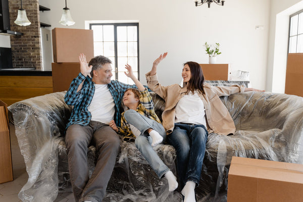 Family sitting on a sofa with boxes around them having just moved home